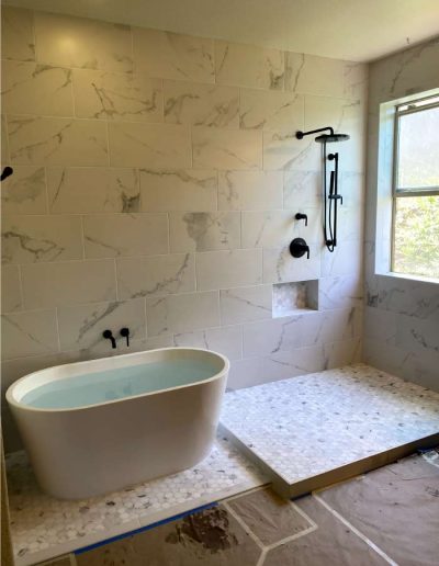 Walk-in shower featuring a linear drain and modern, wall-mounted faucet plumbin